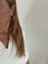 Load image into Gallery viewer, woman wearing gold twisted hoop earrings